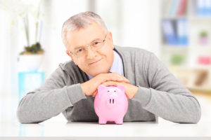 Satisfied mature gentleman posing over a piggy bank at his home